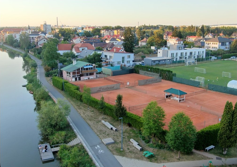 Letecký pohled na areál tenisového klubu v Plané nad Lužnicí: antukové kurty, klubovna a stezka podél řeky Lužnice